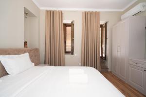 a bedroom with a large white bed and windows at Hotel Dimora 1927 in Tirana