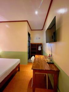 a room with a bed and a table and a tv at Marianne's Guest House in New Agutaya
