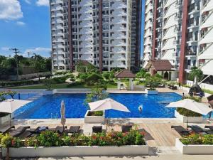 a swimming pool with umbrellas and chairs and buildings at The JOYful Stay in Mactan Island