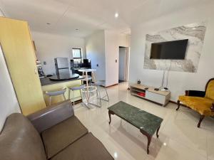 a living room with a couch and a tv on the wall at Sunesta Cottage in Gqeberha