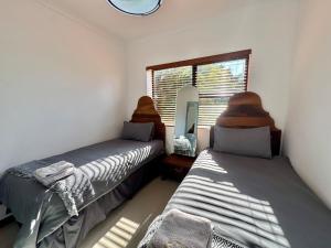 two beds in a room with a mirror and a window at Sunesta Cottage in Gqeberha