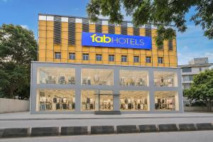 a large yellow building with a blue sign on it at FabHotel Vaishnavi Classic in Secunderabad
