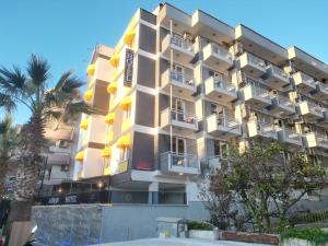 a tall building with balconies and palm trees at Akman City Hotel in Kuşadası