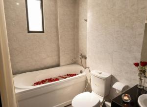 a bathroom with a toilet and a tub with roses in it at Zesty Hostel & Bistro in Nha Trang