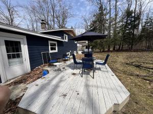 a wooden deck with chairs and an umbrella on a house at Trailside Lake Retreat in Gaylord