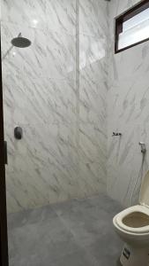 ein weißes Badezimmer mit Toilette und Dusche in der Unterkunft Hotel Pesaban in Tjakranegara