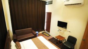 a room with a bed and a chair and a television at Hotel Crystal Rajkot in Rajkot