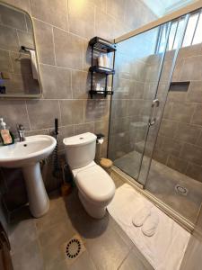 a bathroom with a toilet and a shower and a sink at Elite Apartments Masaka in Kigali +14 photos