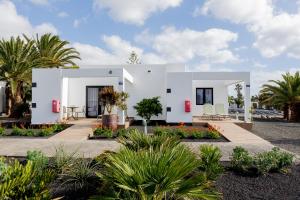 a white house with palm trees and plants at Relaxia Lanzasur Club - Aqualava Water Park in Playa Blanca