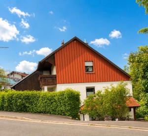 a red and white house with bushes in front of it at Ferienwohnung Maxi in Pottenstein