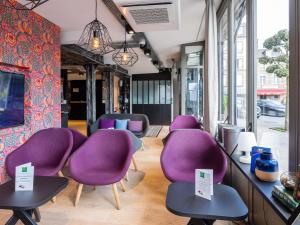 a row of purple chairs in a room with windows at ibis Styles Dinan Centre Ville in Dinan
