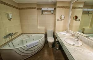 a bathroom with a tub and a toilet and a sink at Arty Grand Hotel in Olympia +9 photos