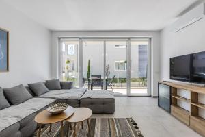 a living room with a large couch and a television at Le Bleu Apartment Pool & Beach by PikHost in Lezhë