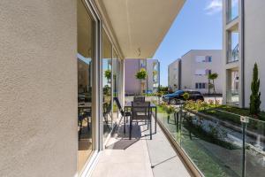 a balcony with glass doors and a table with chairs at Le Bleu Apartment Pool & Beach by PikHost in Lezhë