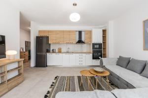 a living room with a couch and a kitchen at Le Bleu Apartment Pool & Beach by PikHost in Lezhë