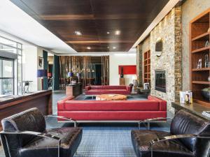 a living room with a red couch and two chairs at Novotel Montréal Aéroport in Dorval