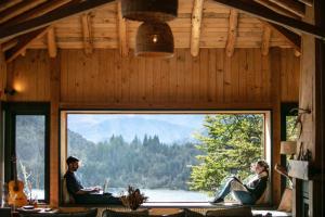 a group of people sitting in a room with a large window at Hermoso Eco Lodge in San Martín de los Andes