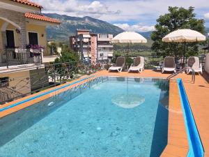 a swimming pool on top of a building with chairs and umbrellas at Family Vacation Home in Gjirokastër