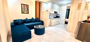 a living room with a blue couch and a kitchen at Yogvan Luxury 1BHK Apartments Tapovan Rishikesh in Rishīkesh