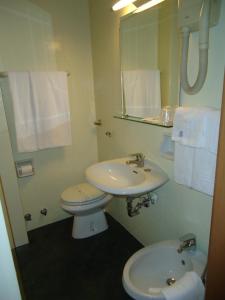ein Badezimmer mit einem Waschbecken, einem WC und einem Spiegel in der Unterkunft Hotel Cristallo Brescia in Brescia