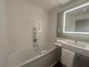 a white bathroom with a tub and a sink at Novotel Suites Rouen Normandie in Rouen +107 photos
