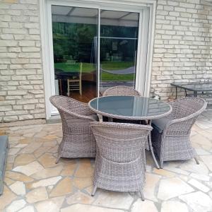 a glass table and chairs on a patio at Chez Nanard et Lili in Bec-de-Mortagne