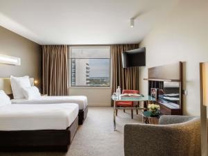 a hotel room with two beds and a tv at Pullman Sydney Olympic Park in Sydney