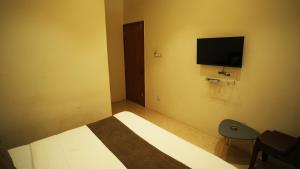a bedroom with a bed and a television on the wall at Hotel Crystal Rajkot in Rajkot +5 photos