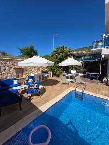 a swimming pool with blue chairs and umbrellas at Mavi Ruya - Modern ground floor duplex apartement with private pool & XL outdoor in Kalkan +54 photos