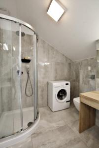 a bathroom with a shower and a washing machine at Apartamenty Rondo in Świnoujście