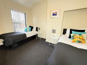 a bedroom with two beds and a window at SPACIOUS 3 BEDROOM HOUSE WITH FREE STREET PARKING and WIFI IDEAL FOR CONTRACTORS by NORTH WEST ACCOMMODATION in Saint Helens
