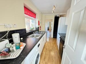 a kitchen with a sink and a refrigerator at SPACIOUS 3 BEDROOM HOUSE WITH FREE STREET PARKING and WIFI IDEAL FOR CONTRACTORS by NORTH WEST ACCOMMODATION in Saint Helens