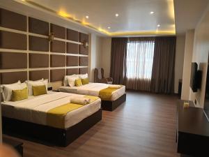 a hotel room with two beds and a television at Borbon Hotel & Restaurant in Jowai