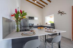 a kitchen with a table with chairs and a vase of flowers at La Villa de Solange - Canope in La Trinité