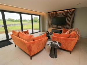 a living room with orange chairs and a flat screen tv at The Cozie Sow in Yeovil
