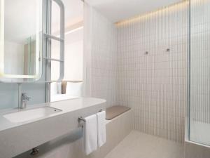 a white bathroom with a sink and a mirror at Pullman Bangkok King Power in Bangkok