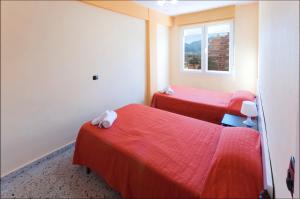 プラヤ・デ・シェラコにあるApartamento Abacoの赤いシーツと窓が備わるベッド2台付きの客室です。