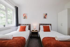 two beds with orange pillows in a bedroom at Spacious 4-Bed Home with Free Parking in Northampton