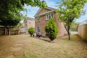 a brick house with a fence and trees in the yard at Spacious 4-Bed Home with Free Parking in Northampton