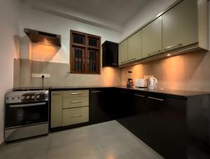 a kitchen with black cabinets and a stove at Hotel Dreamliners in Katunayaka