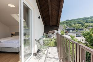 ein Zimmer mit Balkon, mit Bett und Tisch in der Unterkunft odilum - Self-Check-in-Hotel in Mondsee