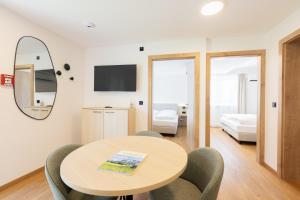 ein Zimmer mit Tisch und Stühlen und ein Schlafzimmer in der Unterkunft odilum - Self-Check-in-Hotel in Mondsee
