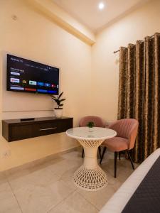 a living room with a tv and a table and chairs at Sukoon stays Bhimtal 3 bed in Bhīm Tāl