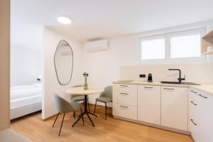eine Küche mit einem Tisch, einer Spüle und einem Spiegel in der Unterkunft odilum - Self-Check-in-Hotel in Mondsee + 73 Fotos