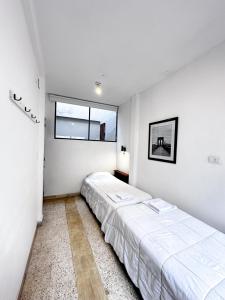 two beds in a white room with two windows at Casa amplia, céntrica y con garage en Junin, BA in Junín