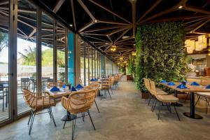 a restaurant with tables and chairs and plants at Flamingo Cát Bà in Cat Ba