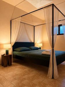a bedroom with a canopy bed with curtains at Villa Iulia - VIBRA in Controguerra