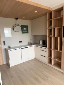 a kitchen with white cabinets and a wooden ceiling at Apartament Sosnowy 45 in Rowy +1 photo