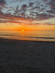 a sunset on a beach with the ocean at Apartament Sosnowy 45 in Rowy