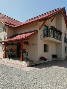 a building with a balcony with flowers on it at Pensiunea Baias in Bîrsana